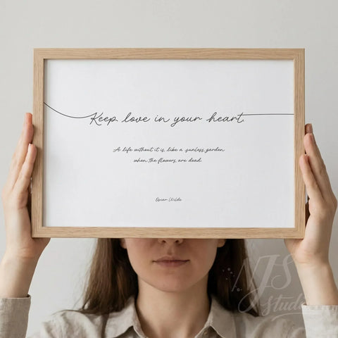 Woman holding a horizontal wood framed print with elegant script typography about love.