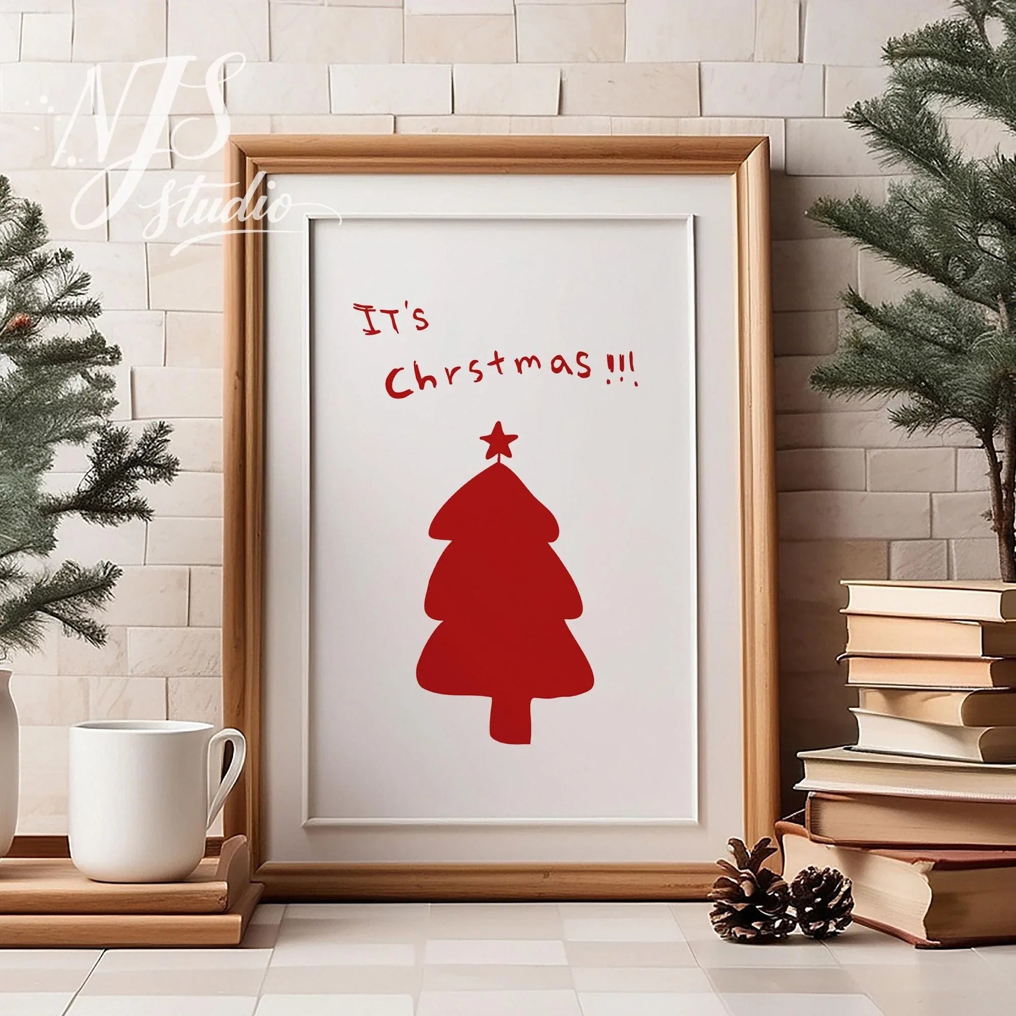 Wood framed whimsical Christmas tree art standing on a table next to books and a coffee mug.