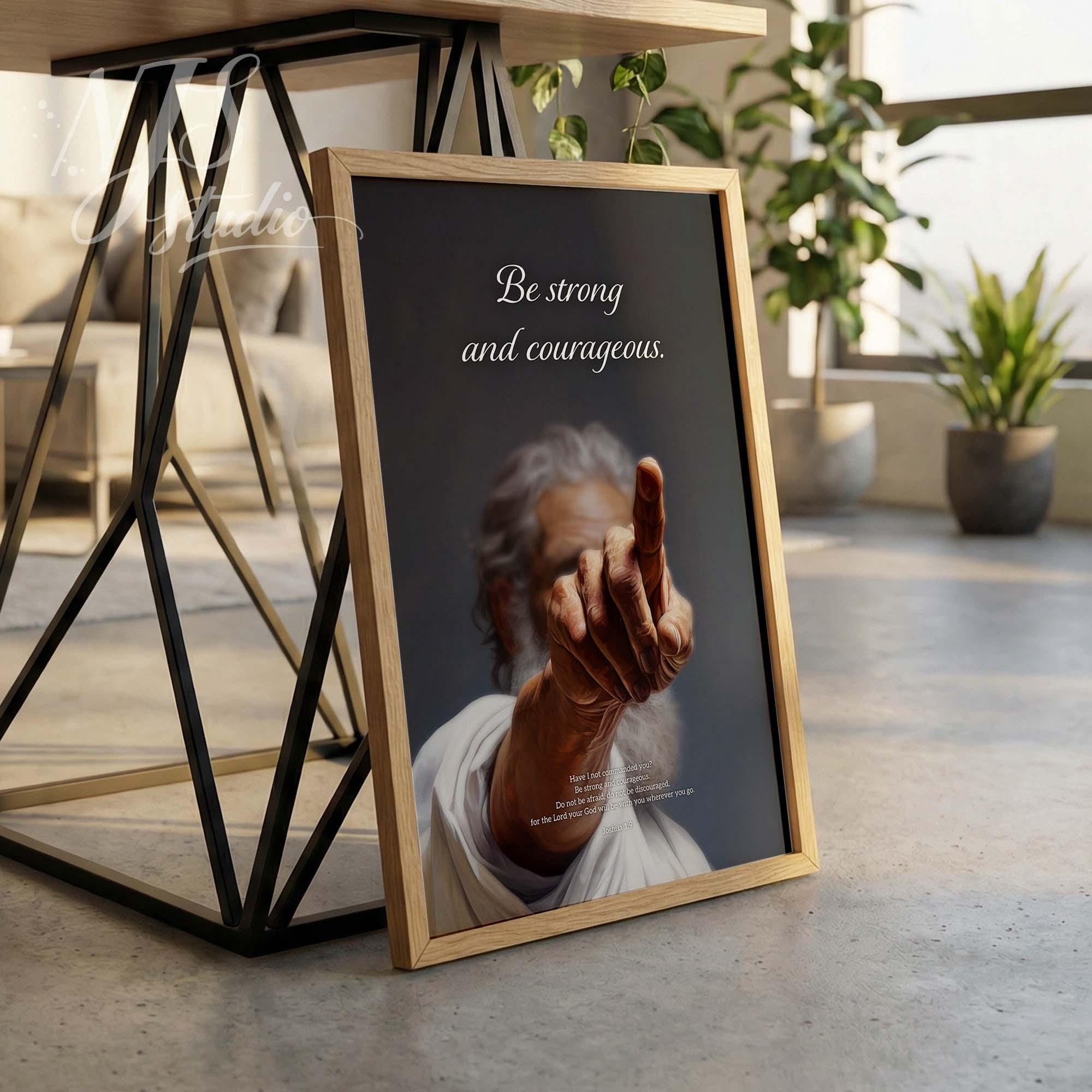Wood framed Joshua 1:9 poster. "Be strong and courageous" bible verse art leaning on table legs for modern home decor.